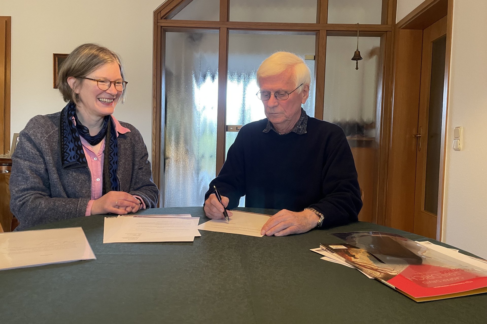 Dr. Ruth Slenczka und Dr. Hans-Georg Lorenz, an einem Tisch sitzend, bei der Unterzeichnung des Vertrags