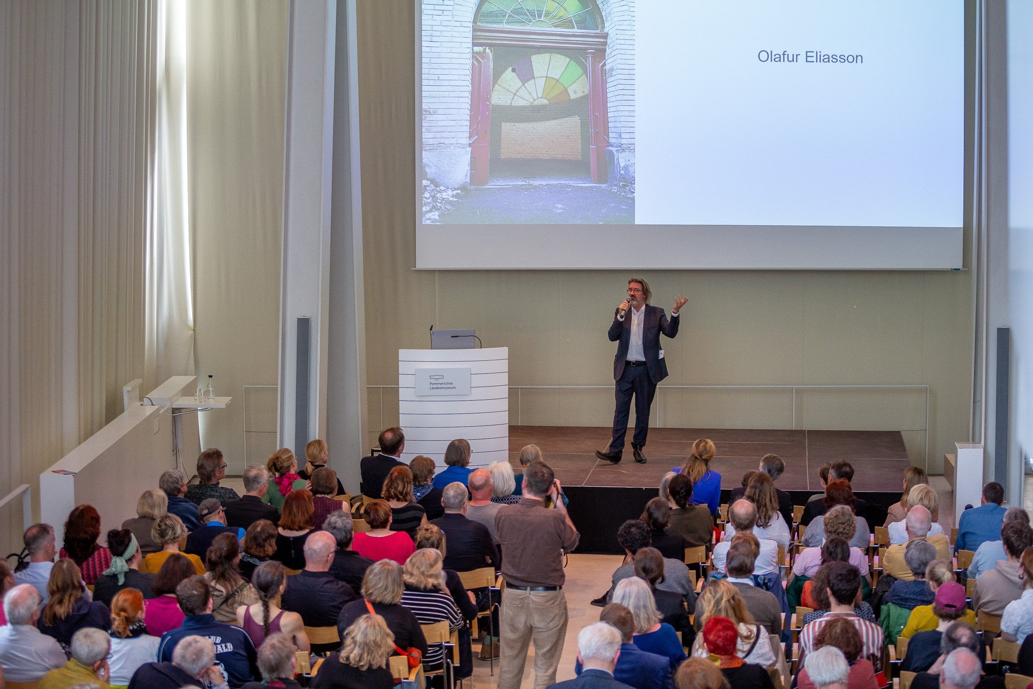 Olafur Eliasson beim Artist Talk, aus leicht erhöhter Sicht, vor Publikum.