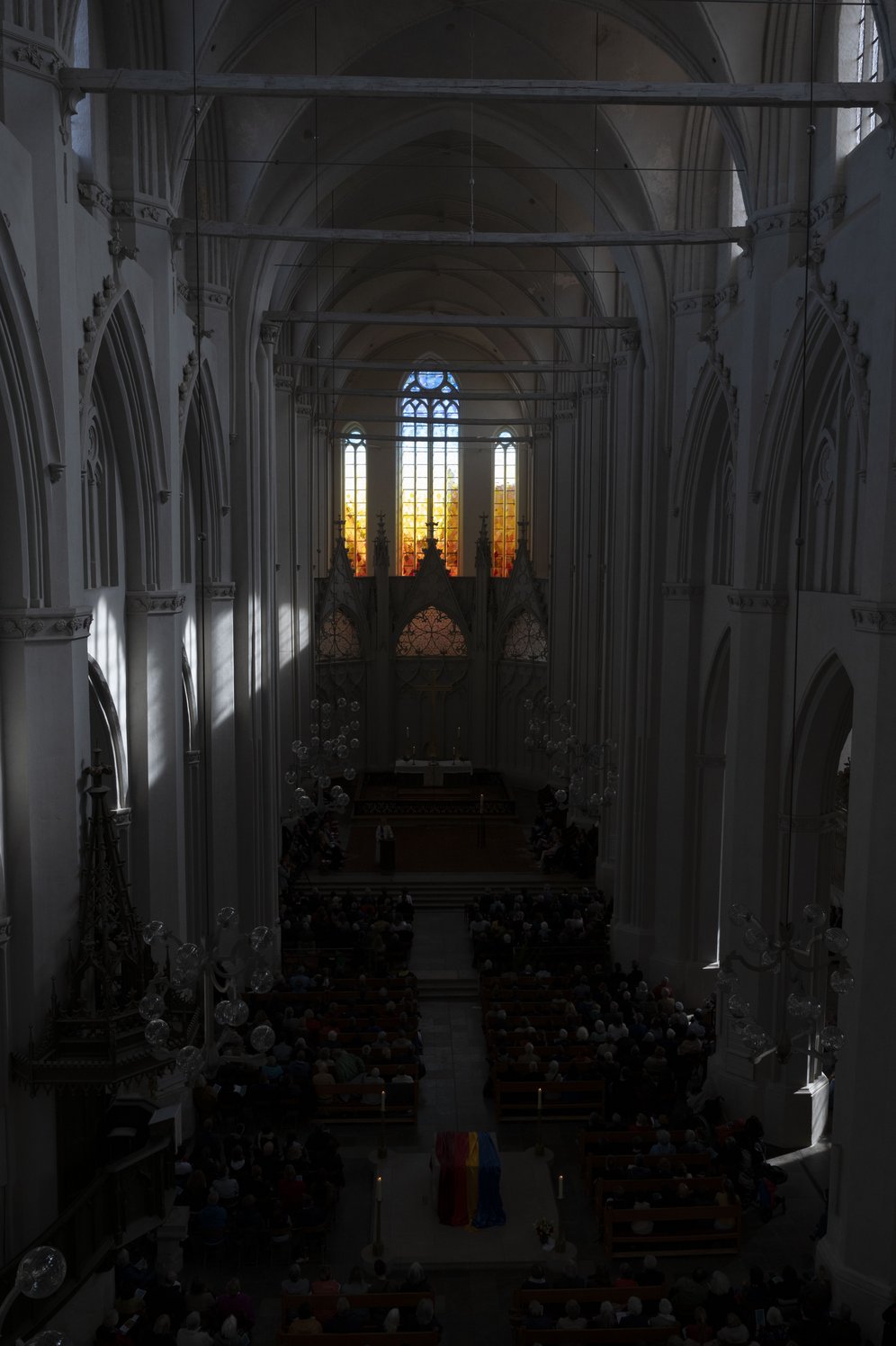 Domfenster von Olafur Eliasson: Blick in den dunklen Kircheninnenraum, am Ende die hellen farbigen Ostfenster.