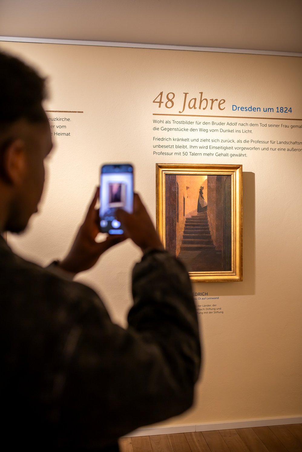 Ein Besucher fotografiert mit dem Smartphone das Gemälde „Zum Licht hinaufsteigende Frau“.
